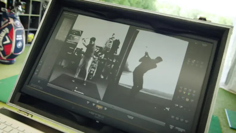 Videoanalyse in der Trainerbox: Monitor zeigt zwei Golfschwünge nebeneinander